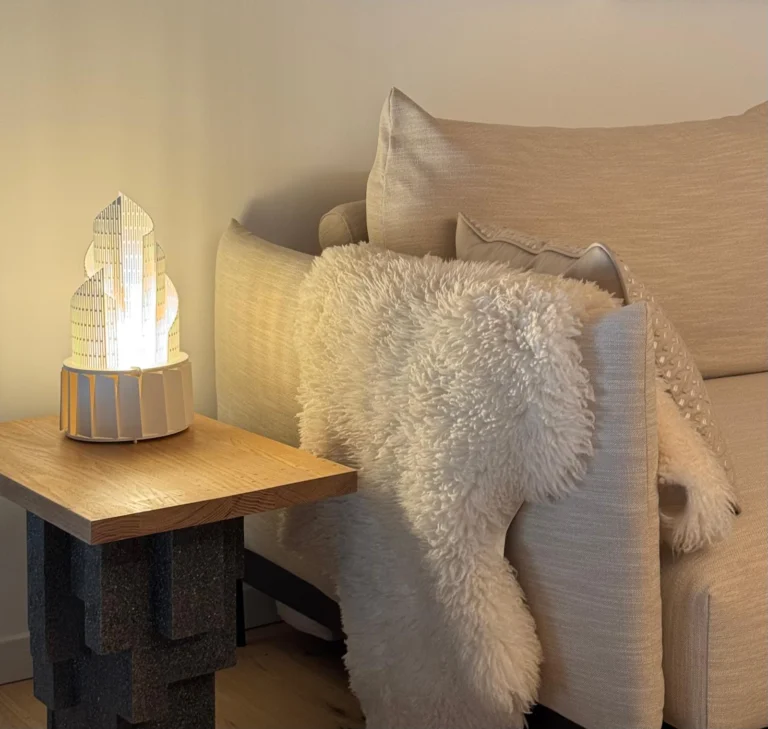 Soft textures and a small illuminated object bring warmth and a sense of discovery to the seating area.